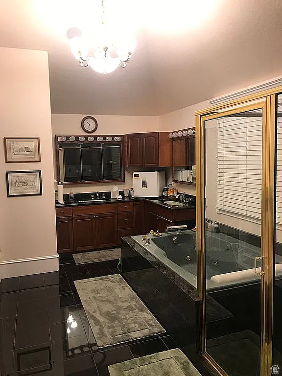 Kitchen with dark countertops, a chandelier, a sink, baseboards, and dark tile patterned floors