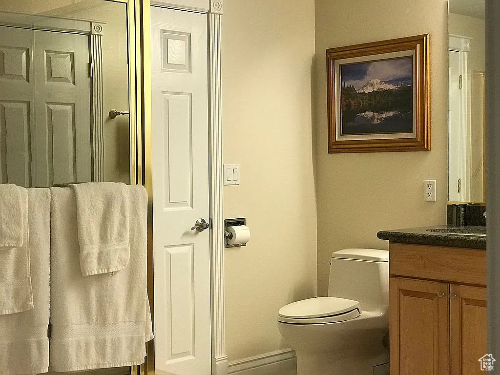 Bathroom featuring vanity, toilet, and baseboards
