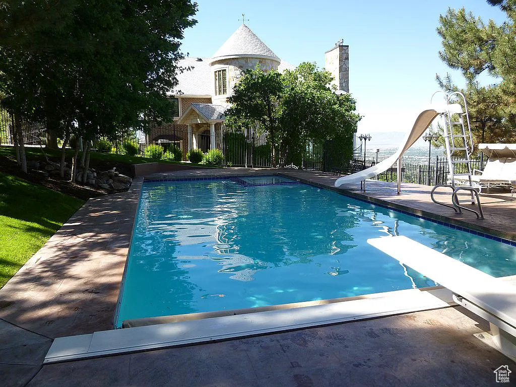 View of swimming pool featuring a water slide and a diving board