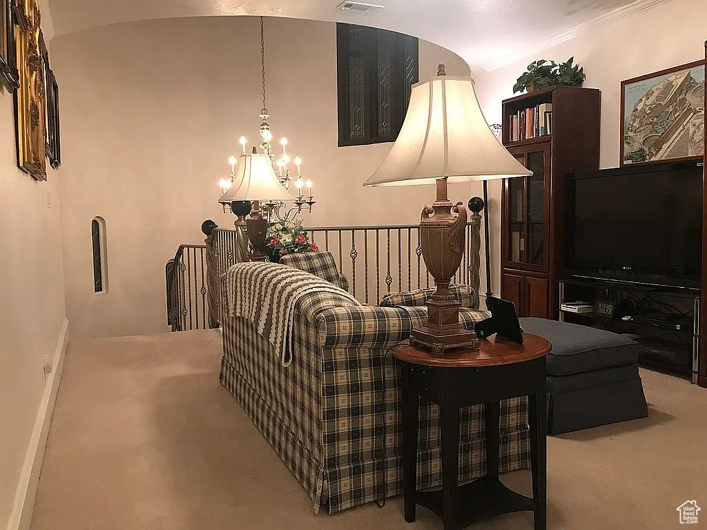 Carpeted living area with a chandelier and baseboards
