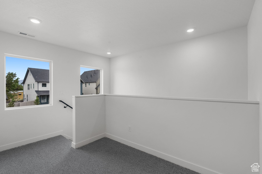 Spare room featuring dark carpet, baseboards, and recessed lighting
