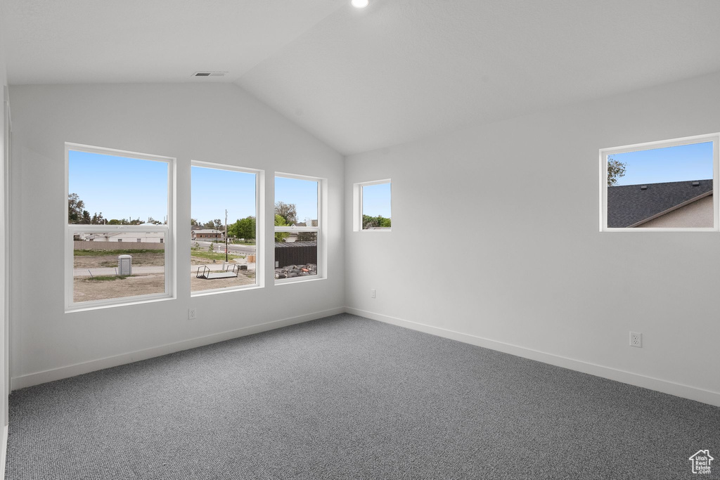 Carpeted empty room with vaulted ceiling and baseboards