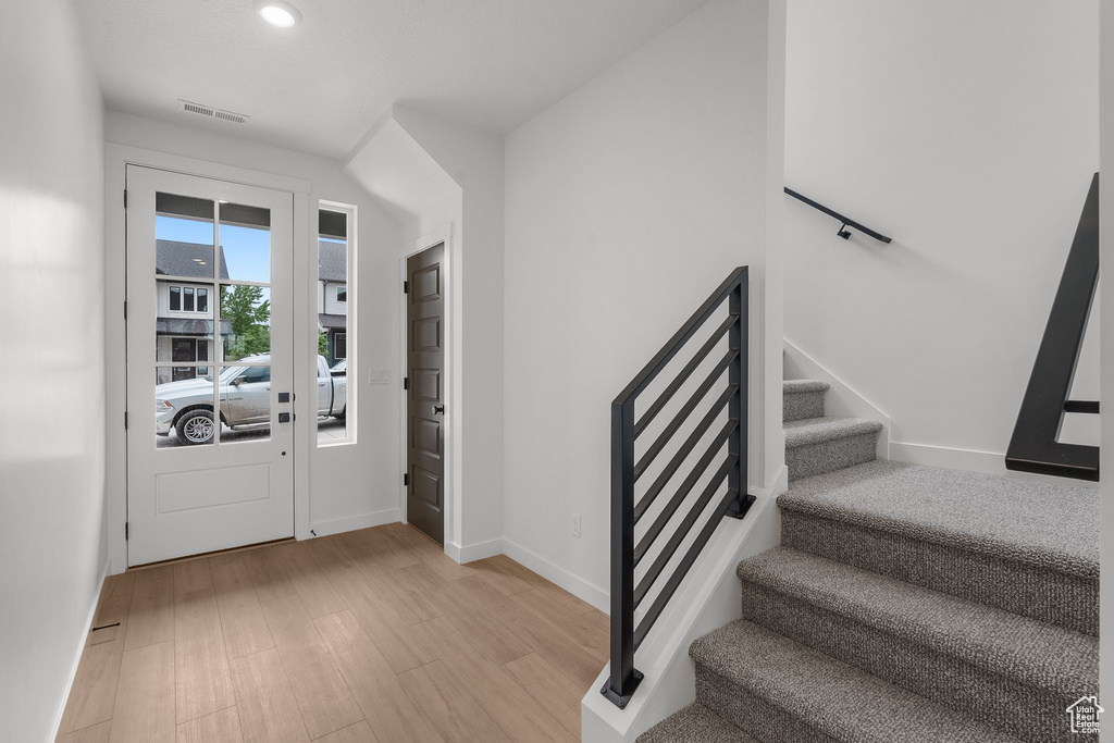 Foyer featuring stairs, light wood-type flooring, baseboards, and recessed lighting