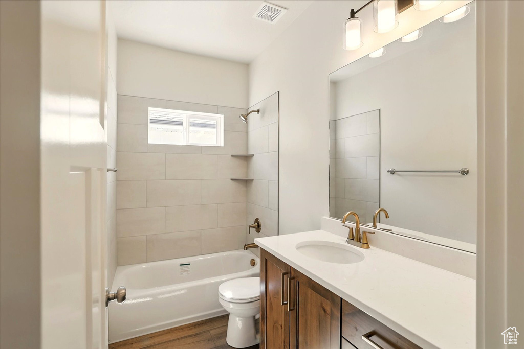 Full bathroom featuring toilet, vanity, shower / bath combination, and wood finished floors