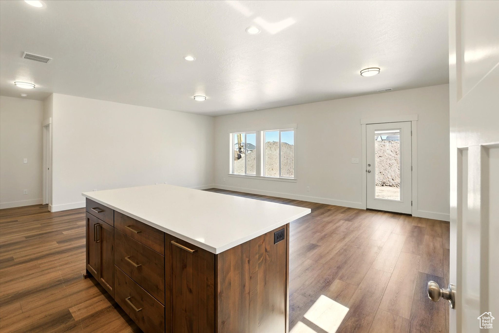 Kitchen featuring dark wood-style floors, light countertops, baseboards, a center island, and recessed lighting