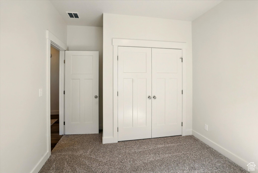 Unfurnished bedroom featuring carpet floors, baseboards, and a closet