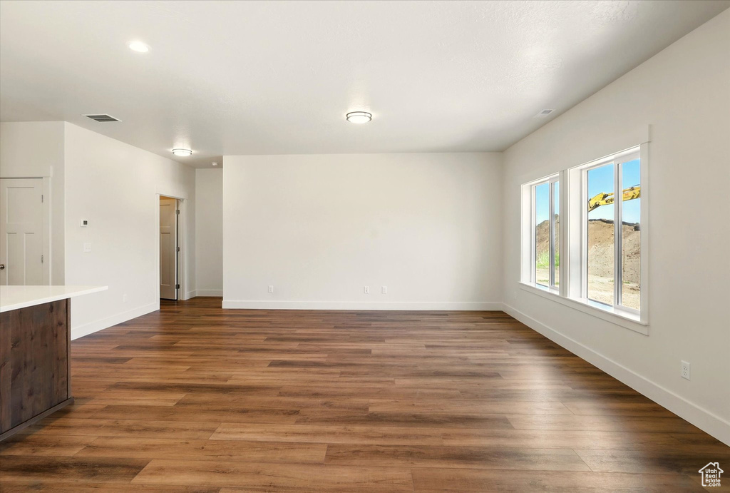 Unfurnished living room featuring dark wood-style flooring and baseboards