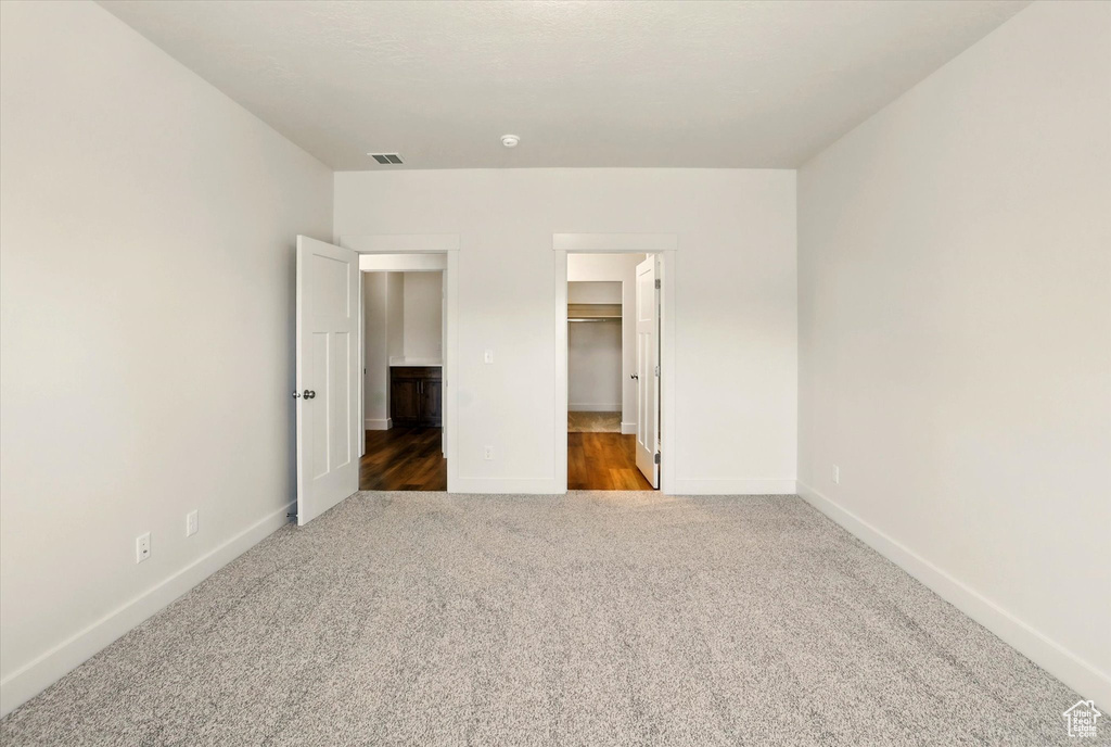Unfurnished bedroom featuring carpet floors, baseboards, a spacious closet, and a closet