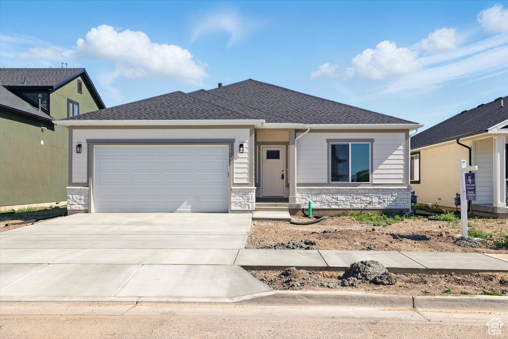 View of front of house with concrete driveway, an attached garage, and stone siding