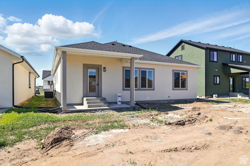 Back of house featuring cooling unit, stucco siding, and roof with shingles