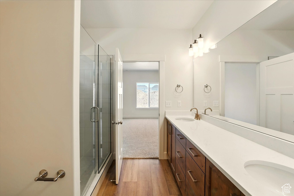 Bathroom with double vanity, a stall shower, and wood finished floors