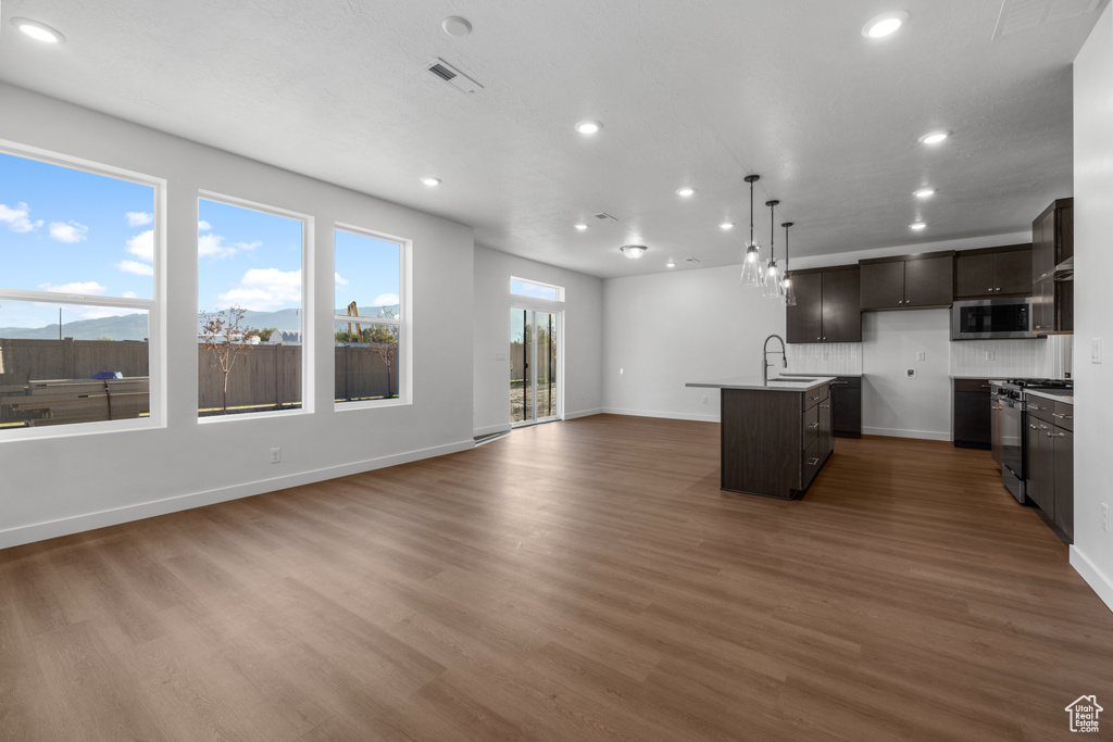 Kitchen featuring stainless steel appliances, open floor plan, recessed lighting, an island with sink, and dark wood-style floors