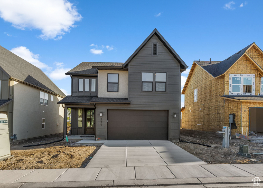 View of front of property featuring an attached garage, driveway, and roof with shingles