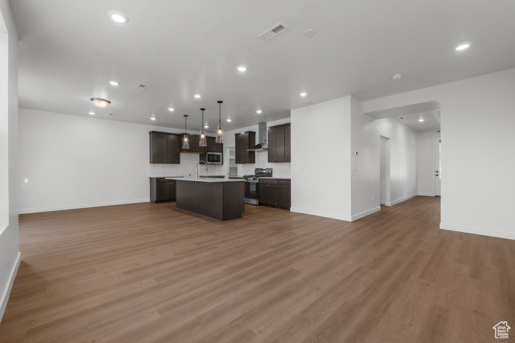 Kitchen with open floor plan, stainless steel appliances, recessed lighting, a center island with sink, and baseboards