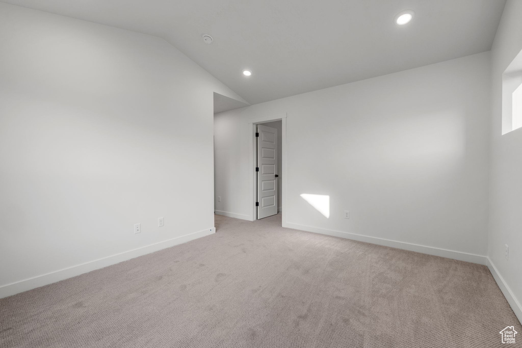 Unfurnished room featuring light colored carpet, baseboards, recessed lighting, and lofted ceiling