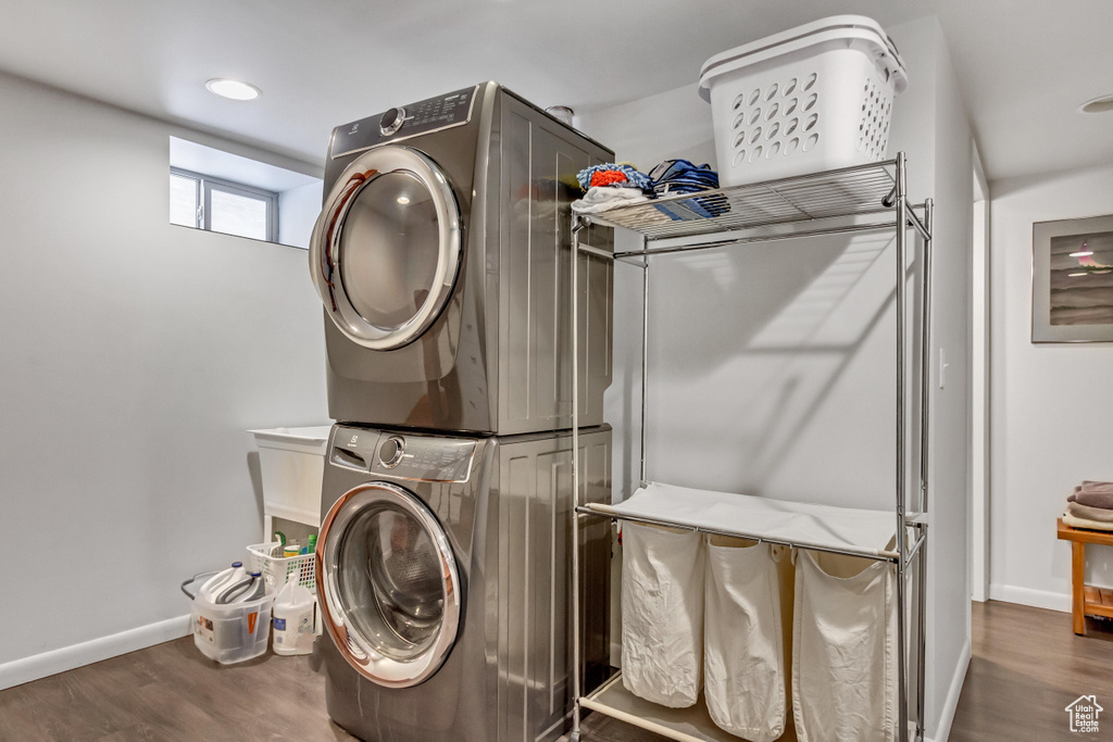 Laundry area with stacked washing machine and dryer, baseboards, wood finished floors, and recessed lighting