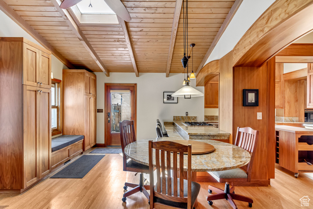 Dining space featuring wood ceiling, light wood finished floors, and a skylight