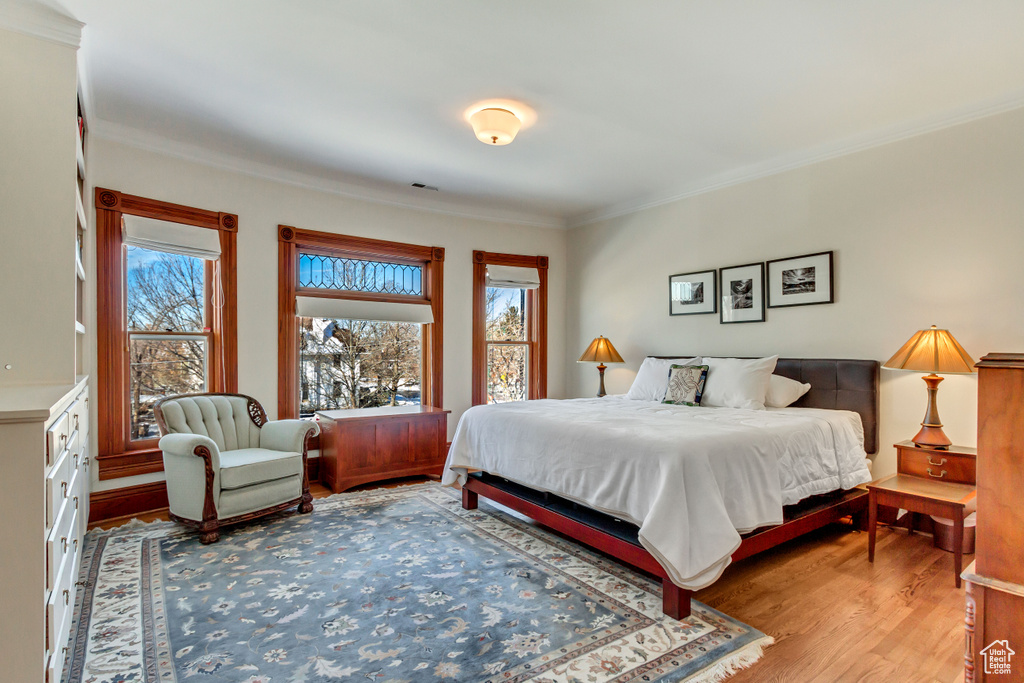 Bedroom featuring multiple windows, wood finished floors, and crown molding