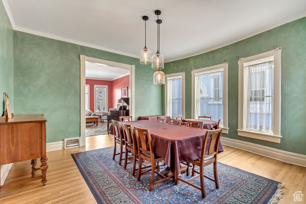 Dining space with wood finished floors, ornamental molding, and baseboards