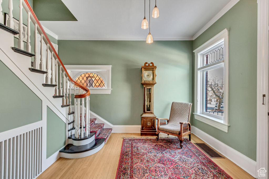 Living area featuring healthy amount of natural light, crown molding, wood finished floors, stairway, and baseboards