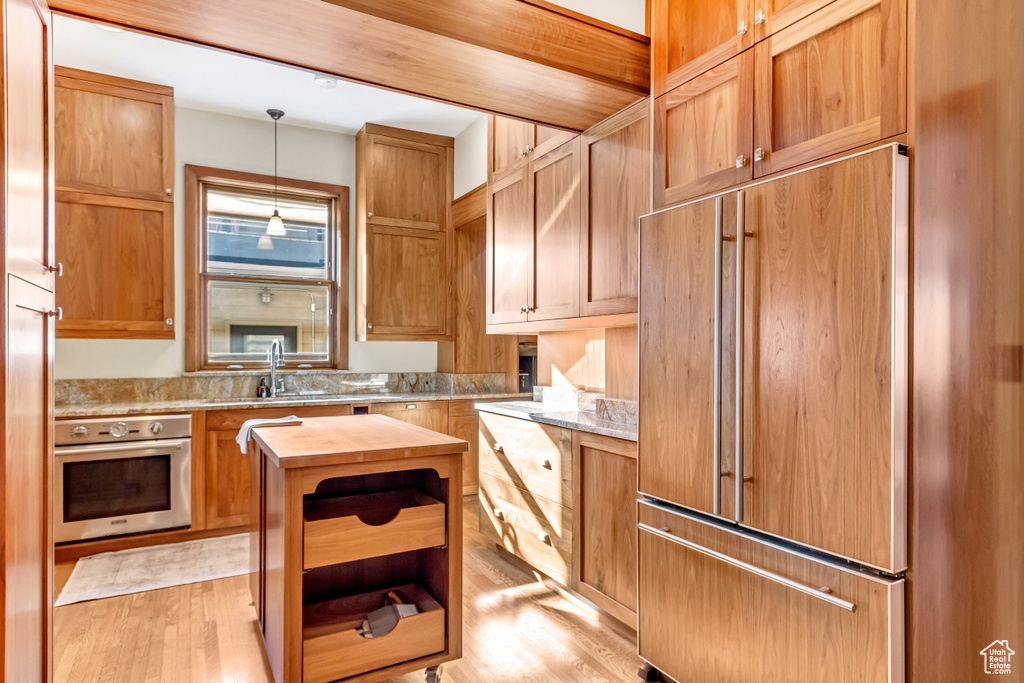 Kitchen with oven, paneled built in refrigerator, wooden counters, open shelves, and a sink