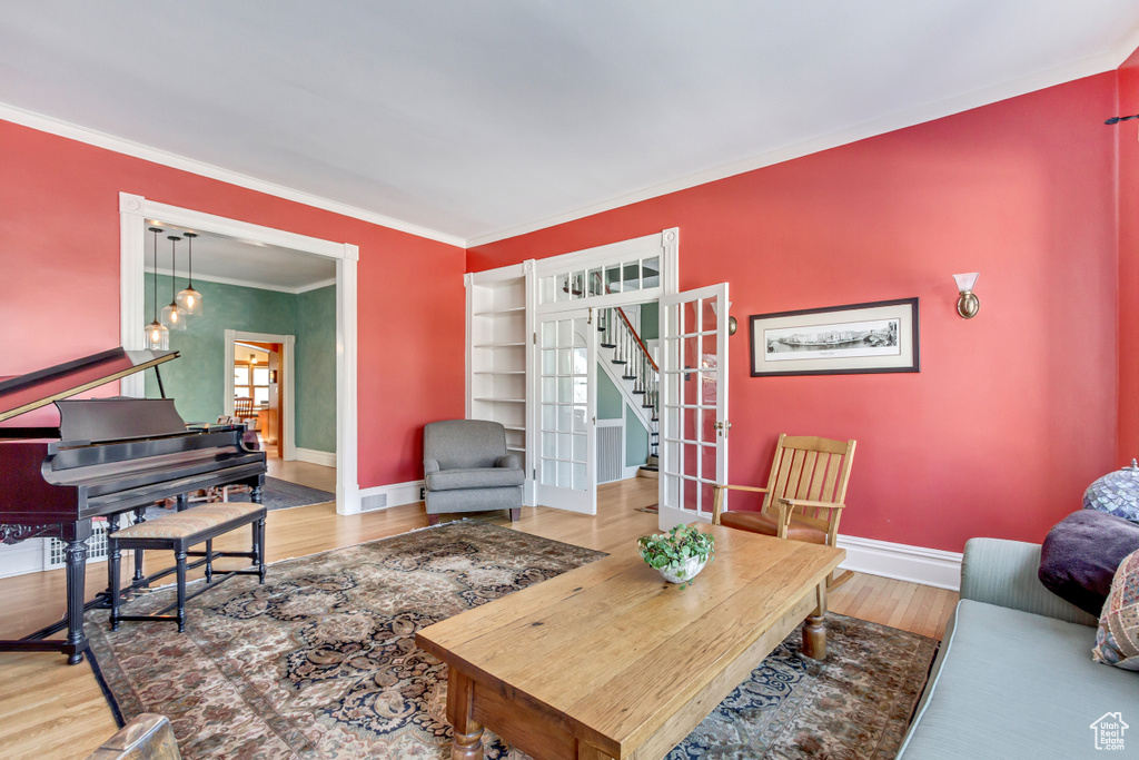 Living room featuring stairway, crown molding, baseboards, wood finished floors, and a chandelier