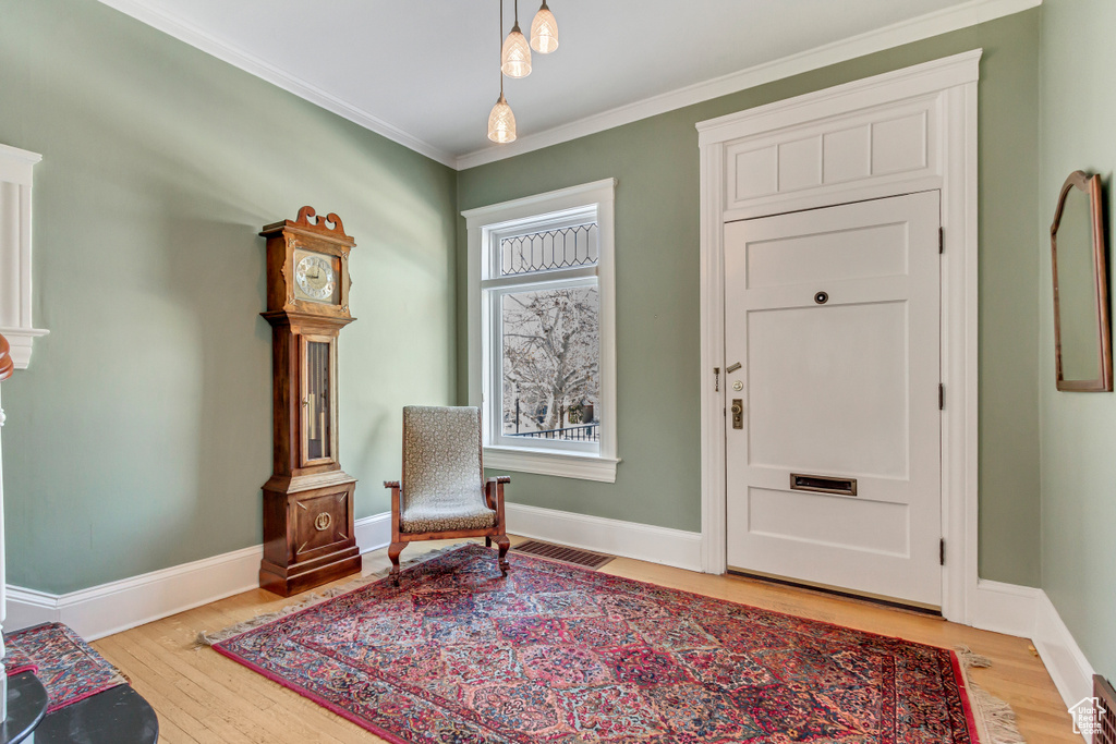 Living area featuring light wood finished floors, baseboards, and ornamental molding