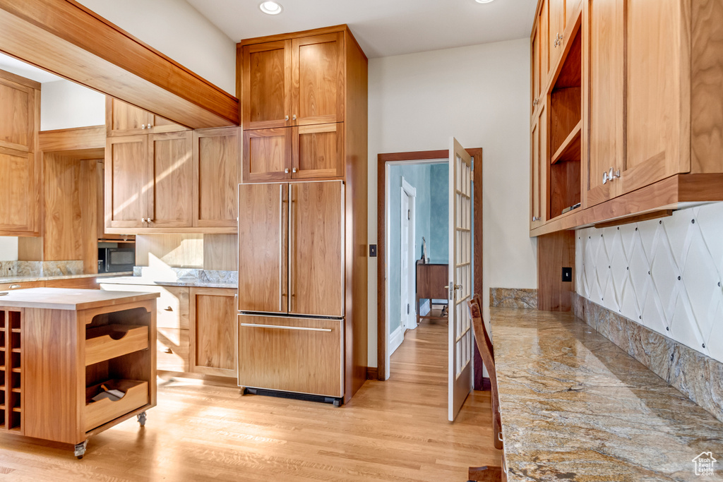 Kitchen featuring paneled fridge, open shelves, light countertops, light wood finished floors, and recessed lighting