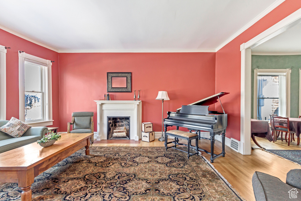 Living room featuring wood finished floors, crown molding, a fireplace with flush hearth, and baseboards