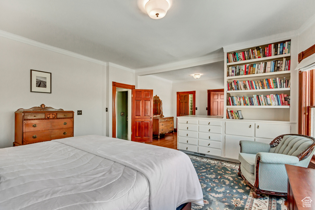 Bedroom with ornamental molding and wood finished floors