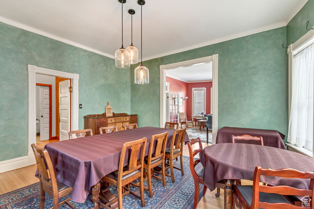 Dining room with wood finished floors, plenty of natural light, crown molding, and baseboards