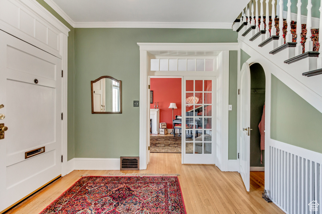 Foyer with light wood-style flooring, baseboards, and ornamental molding