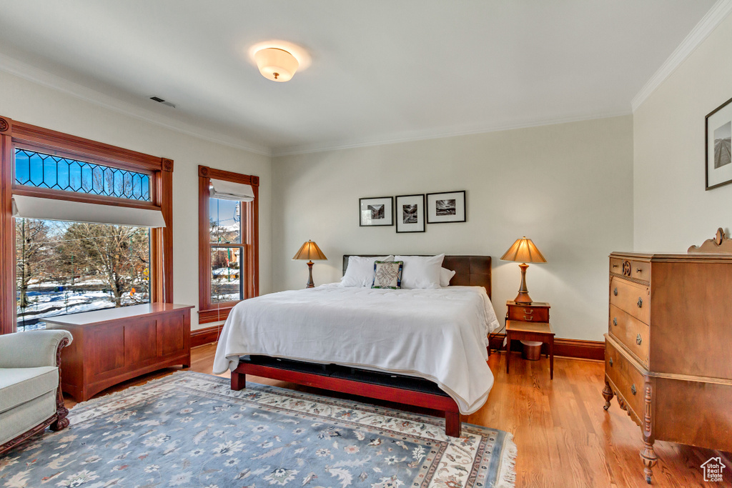 Bedroom with light wood-style floors, crown molding, and baseboards