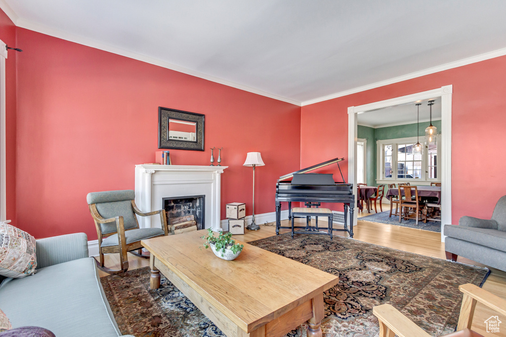 Living area with ornamental molding, wood finished floors, and a glass covered fireplace