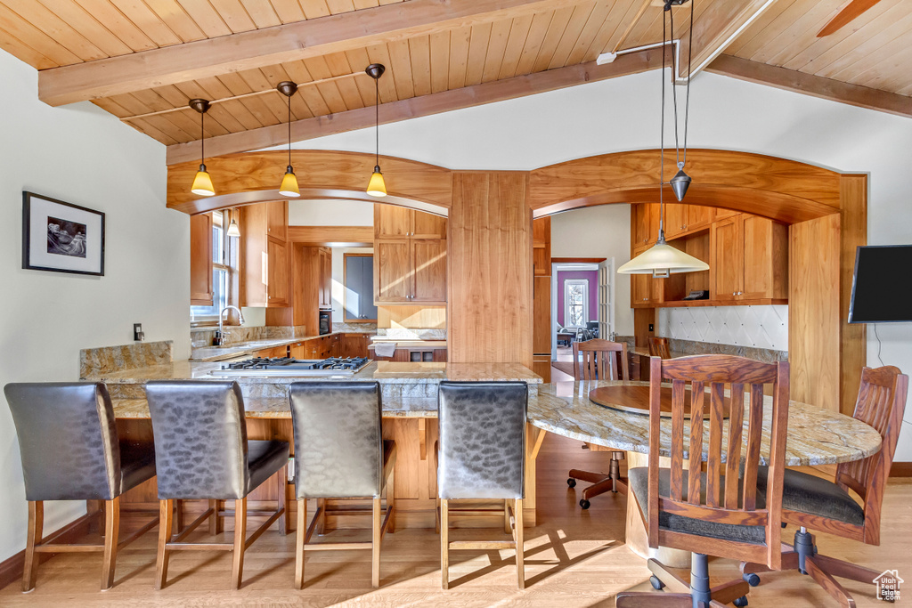 Kitchen featuring light wood-style floors, a peninsula, wood ceiling, stainless steel gas stovetop, and light stone countertops