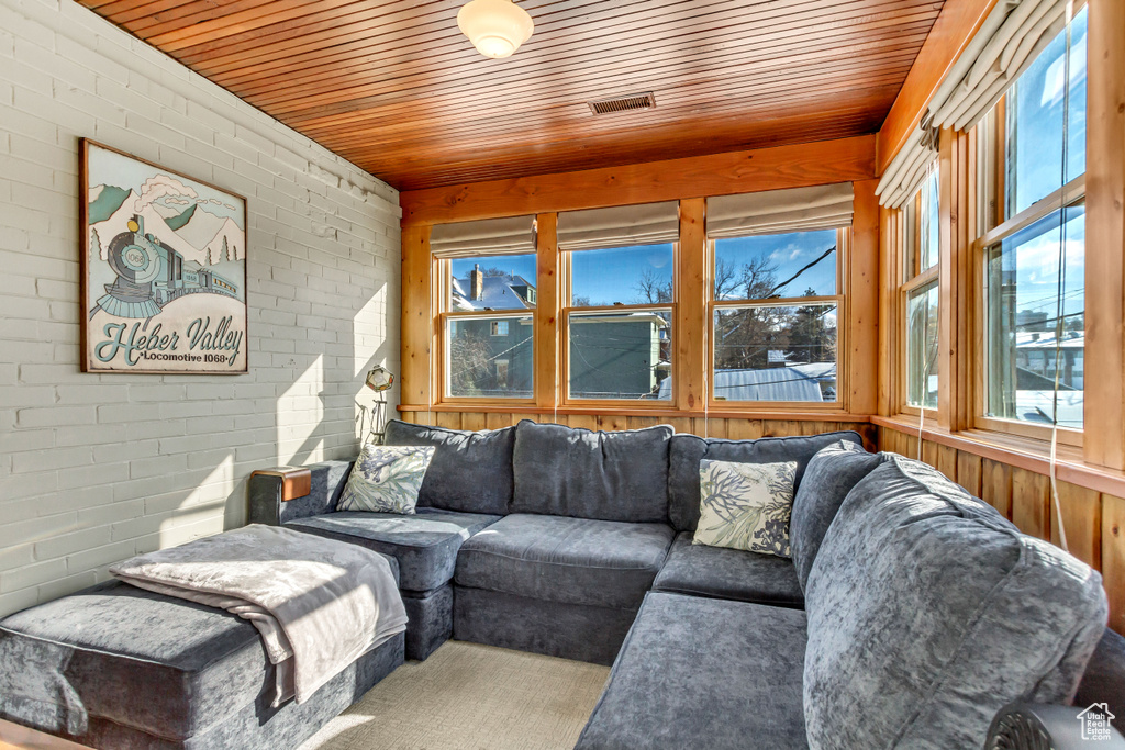 Living room with wood ceiling, brick wall, and wooden walls