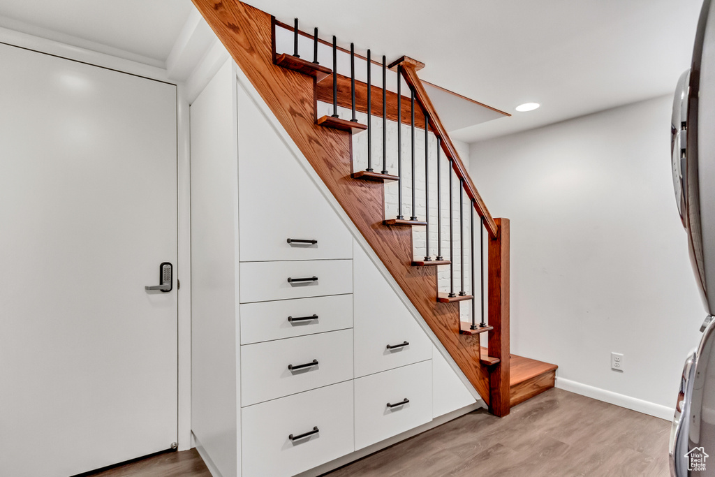 Stairs with wood finished floors, baseboards, and recessed lighting