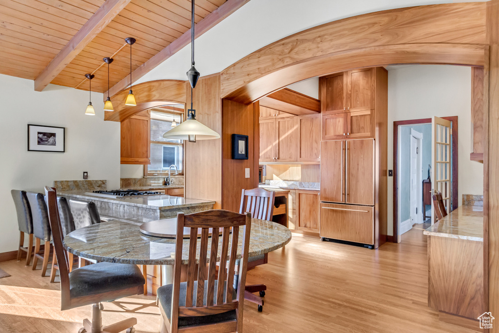 Dining space featuring arched walkways, light wood-type flooring, wooden ceiling, and baseboards