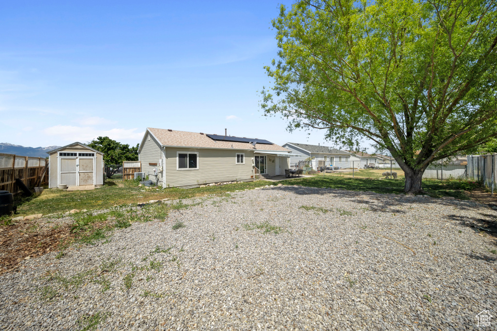Back of house with a fenced backyard and roof mounted solar panels