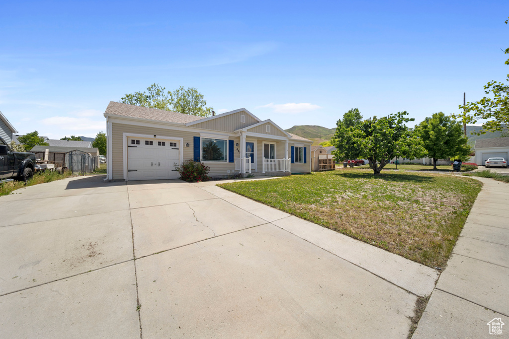 Single story home featuring an attached garage, driveway, a porch, and a front lawn