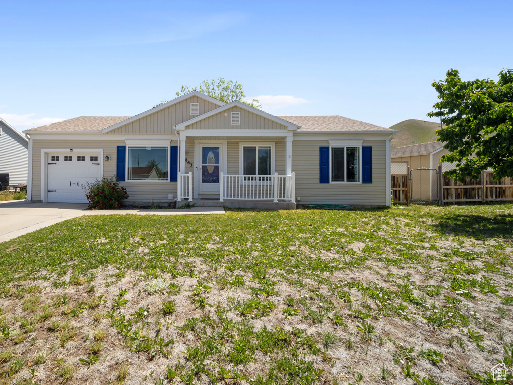 Single story home featuring a garage, covered porch, concrete driveway, board and batten siding, and roof with shingles