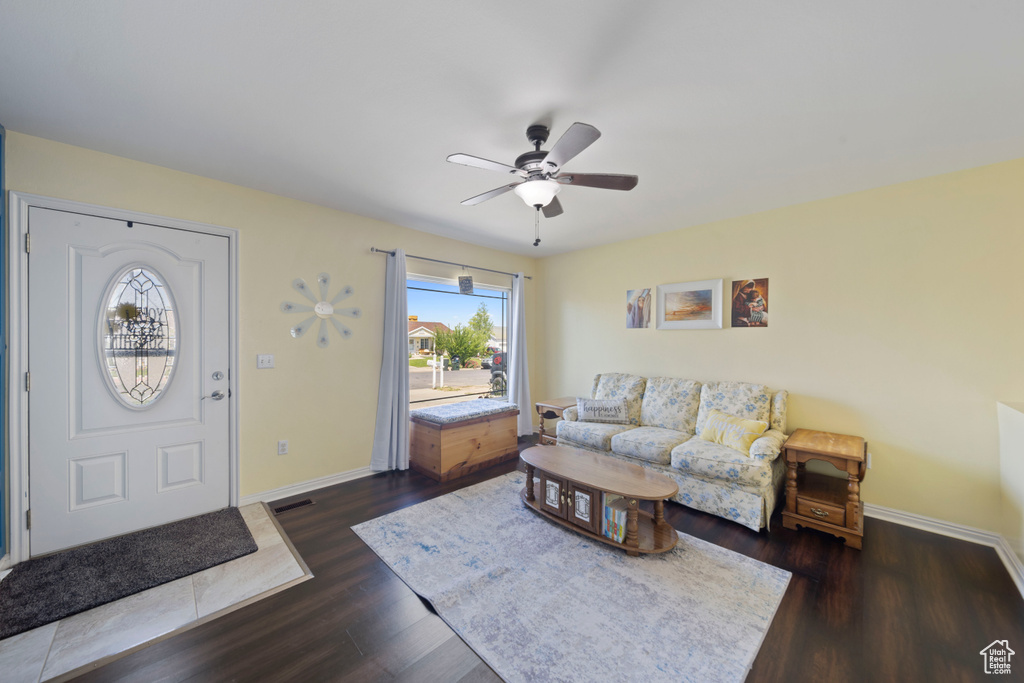 Living area with dark wood-style floors, a ceiling fan, and baseboards