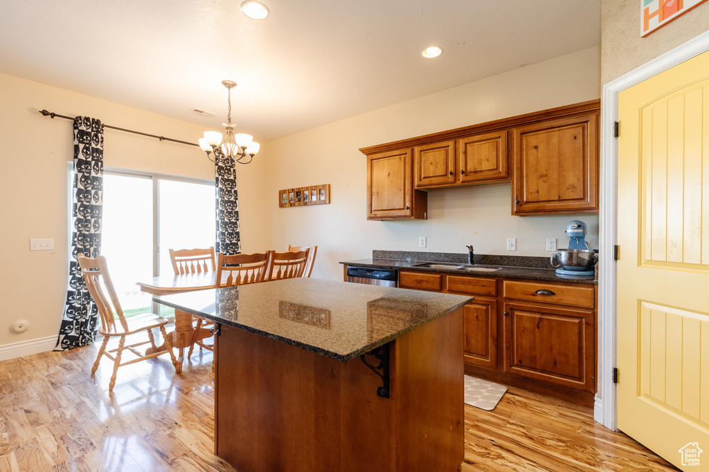 Kitchen with a sink, a chandelier, brown cabinetry, light wood-type flooring, and a center island
