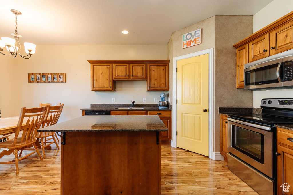 Kitchen featuring stainless steel appliances, light wood-style floors, a sink, a center island, and a chandelier