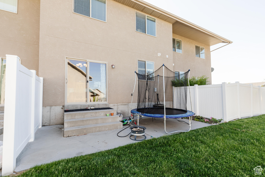 Back of property with a trampoline, entry steps, and stucco siding