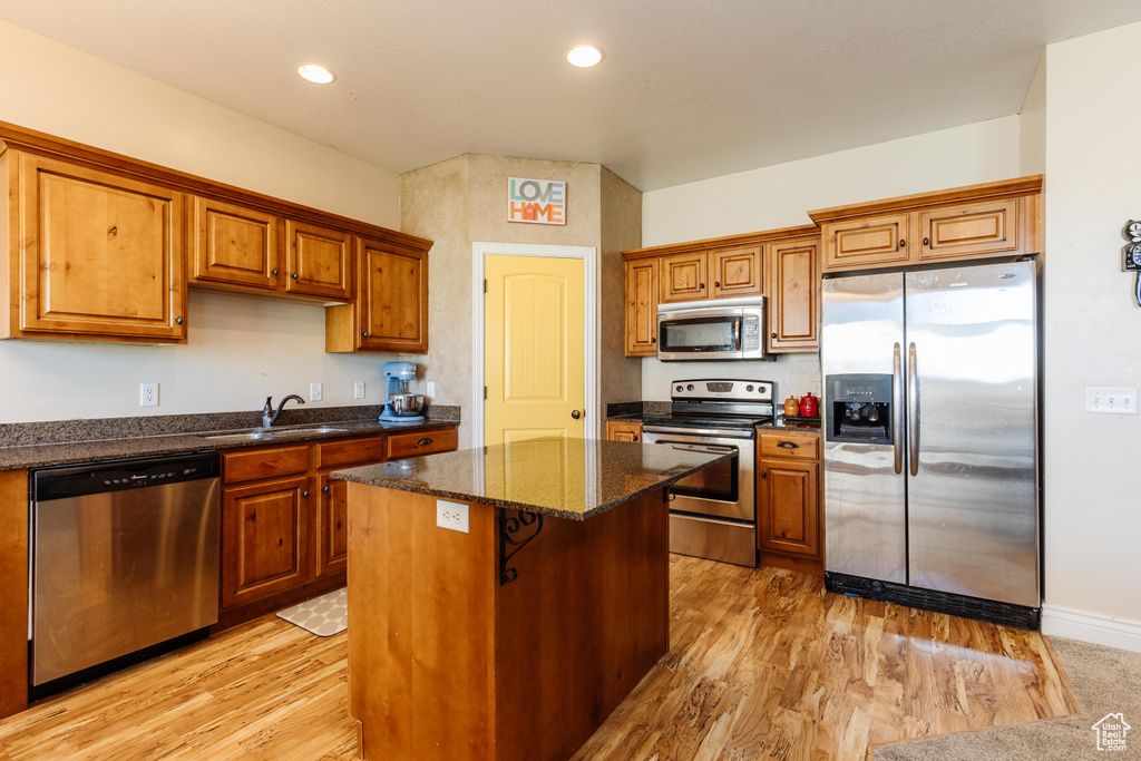 Kitchen with stainless steel appliances, a sink, a kitchen island, brown cabinets, and recessed lighting