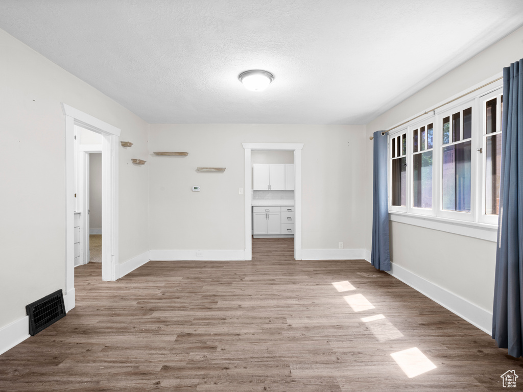 Spare room with baseboards, wood finished floors, and a textured ceiling