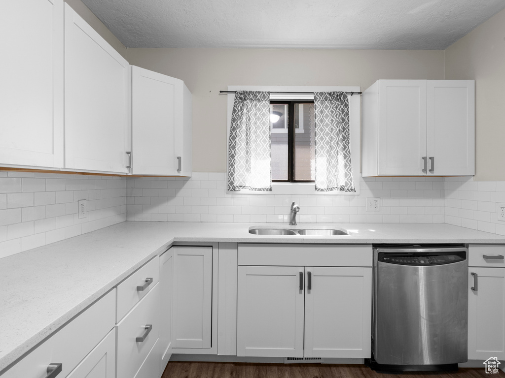 Kitchen featuring stainless steel dishwasher, a sink, white cabinets, light countertops, and a textured ceiling