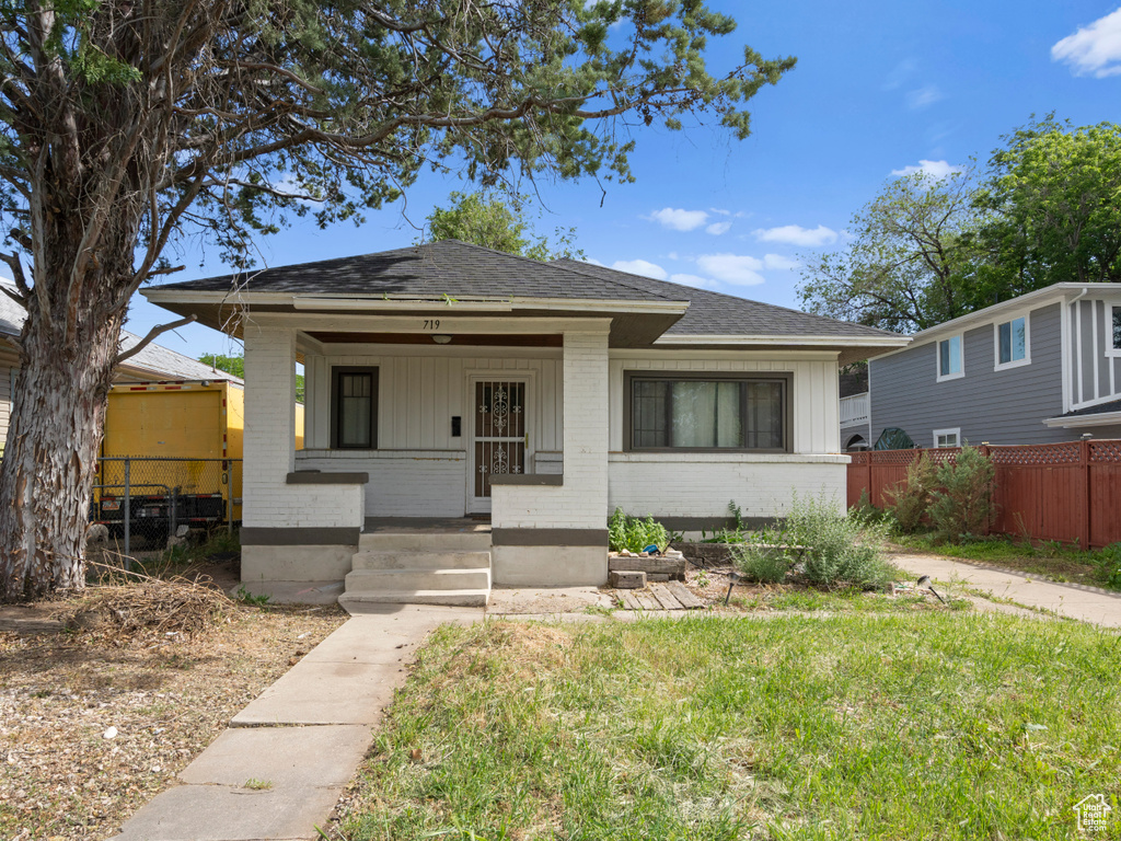 Bungalow-style home with brick siding, a porch, a shingled roof, and board and batten siding