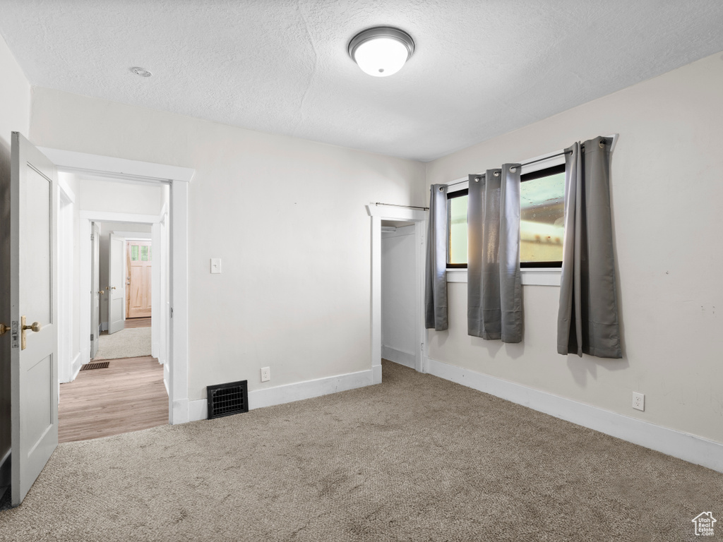 Unfurnished bedroom with carpet floors, a textured ceiling, a closet, and baseboards